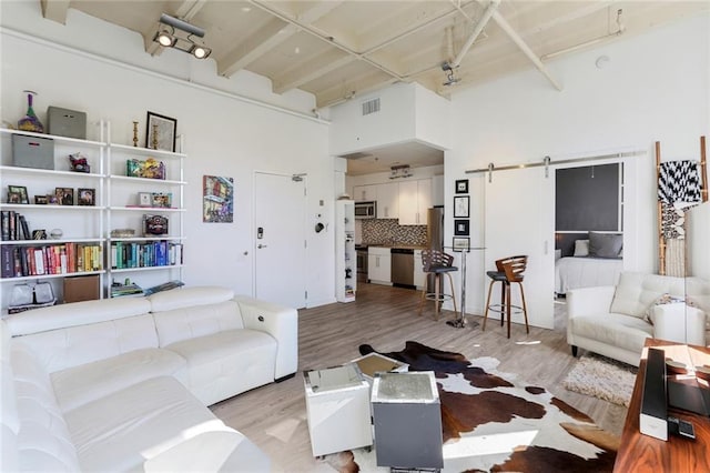 835 Julia St Unit 18, New Orleans, LA 70113 - living area with wood finished floors, a barn door, a towering ceiling, and beam ceiling