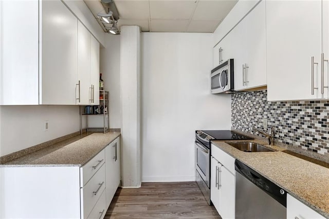 835 Julia St Unit 18, New Orleans, LA 70113 - kitchen with stainless steel appliances, a drop ceiling, decorative backsplash, wood finished floors, and white cabinetry