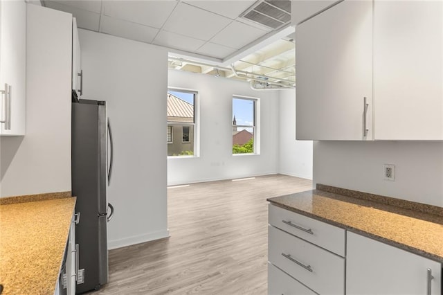 835 Julia St Unit 18, New Orleans, LA 70113 - kitchen with freestanding refrigerator, light wood finished floors, a paneled ceiling, baseboards, and light stone counters