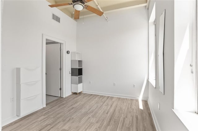 835 Julia St Unit 18, New Orleans, LA 70113 - unfurnished bedroom featuring light wood-style floors, baseboards, a ceiling fan, and a towering ceiling