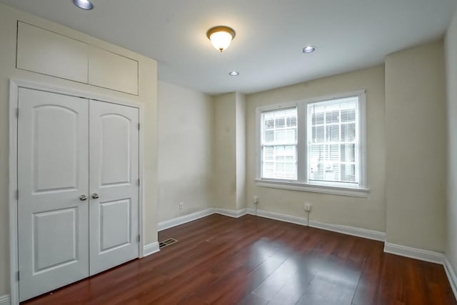 unfurnished bedroom with dark wood-type flooring and a closet