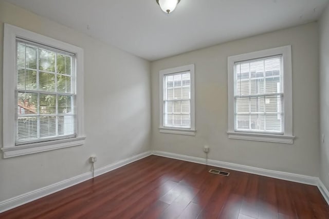 unfurnished room featuring a healthy amount of sunlight and dark hardwood / wood-style flooring