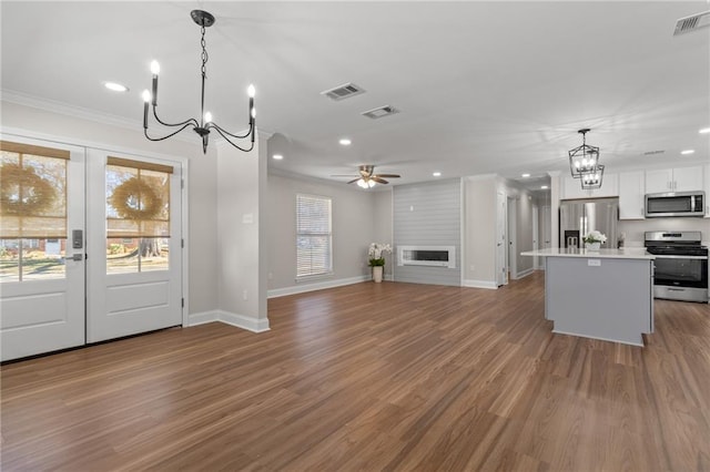 kitchen with appliances with stainless steel finishes, a center island, pendant lighting, and white cabinets