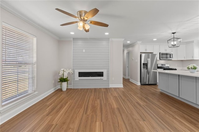 unfurnished living room featuring ornamental molding, a fireplace, light hardwood / wood-style floors, and ceiling fan