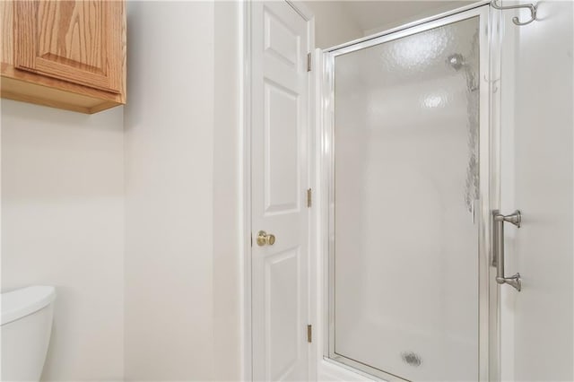 bathroom with a shower with door and toilet