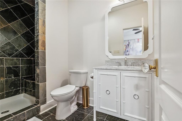 bathroom featuring a tile shower, vanity, and toilet