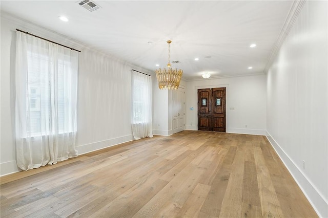 empty room with an inviting chandelier, crown molding, and light hardwood / wood-style flooring