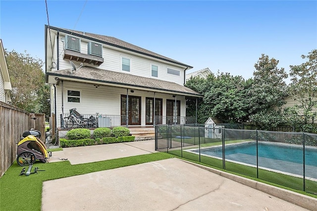 rear view of house featuring a fenced in pool and a patio area