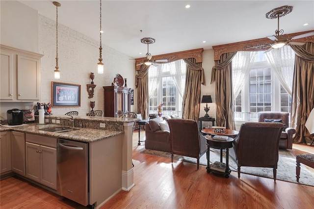 kitchen featuring pendant lighting, sink, dark stone counters, ceiling fan, and light hardwood / wood-style flooring