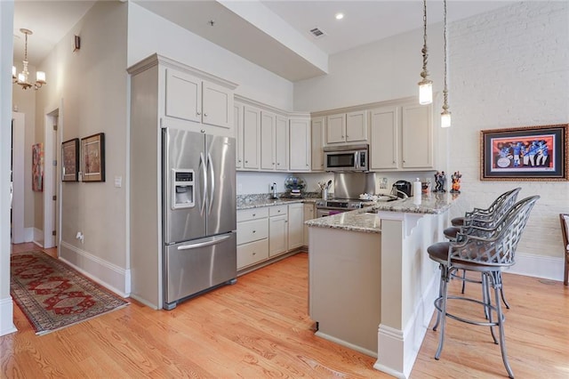 kitchen featuring pendant lighting, a kitchen bar, kitchen peninsula, and appliances with stainless steel finishes