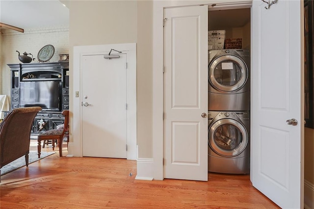 laundry area featuring stacked washing maching and dryer and light wood-type flooring