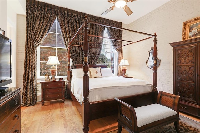 bedroom featuring wood-type flooring, brick wall, and ceiling fan