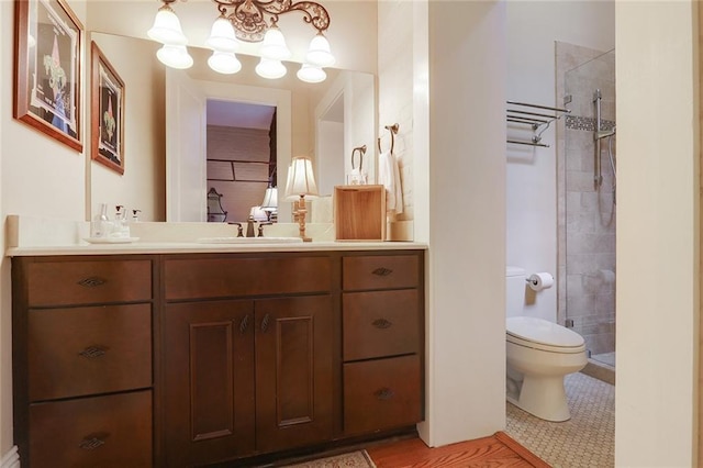 bathroom featuring vanity, a tile shower, tile patterned floors, and toilet