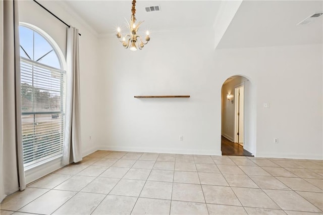 tiled empty room featuring an inviting chandelier and ornamental molding