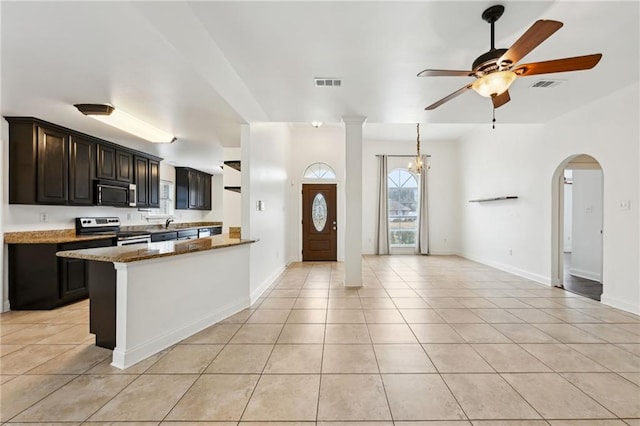 kitchen with stainless steel appliances, light tile patterned flooring, dark stone countertops, and ceiling fan