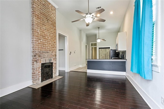 unfurnished living room featuring a brick fireplace and dark wood-type flooring