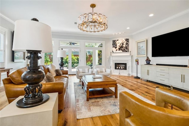 living room featuring crown molding, an inviting chandelier, french doors, and light hardwood / wood-style flooring