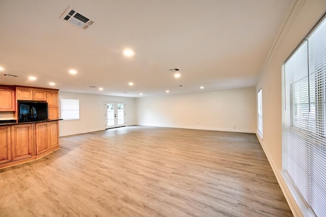 unfurnished living room with crown molding, light hardwood / wood-style floors, and french doors