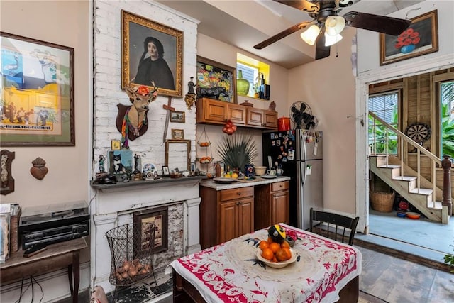 kitchen with ceiling fan, a high end fireplace, hardwood / wood-style floors, and stainless steel refrigerator