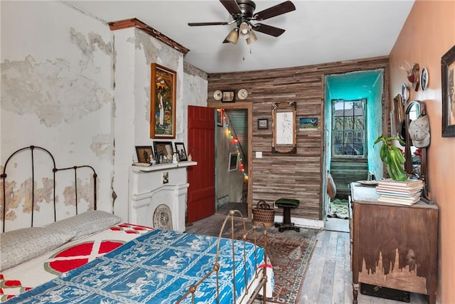 bedroom featuring ceiling fan, hardwood / wood-style floors, and wooden walls