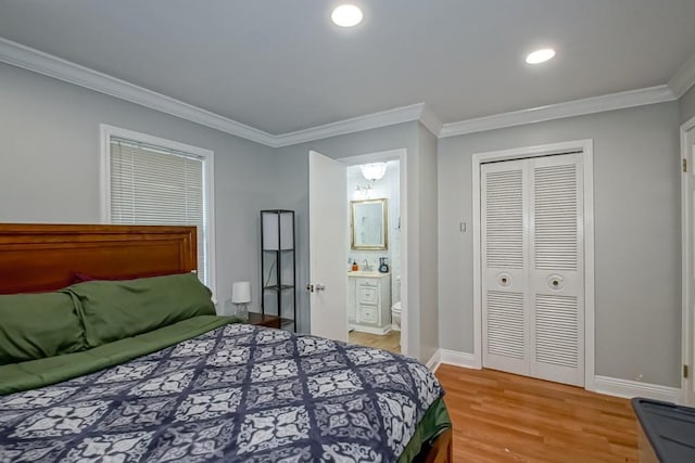 bedroom featuring hardwood / wood-style flooring, crown molding, connected bathroom, and a closet