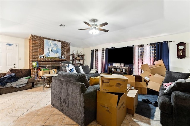 tiled living room with ceiling fan, lofted ceiling, and a fireplace