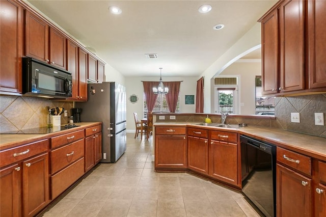 kitchen featuring pendant lighting, black appliances, sink, a chandelier, and kitchen peninsula