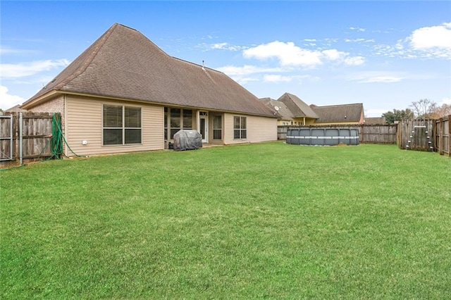 back of property featuring a yard and a covered pool