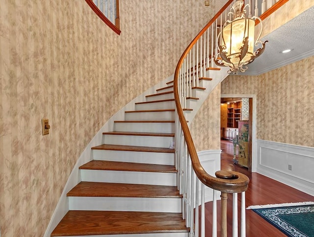 staircase with crown molding, an inviting chandelier, and a textured ceiling