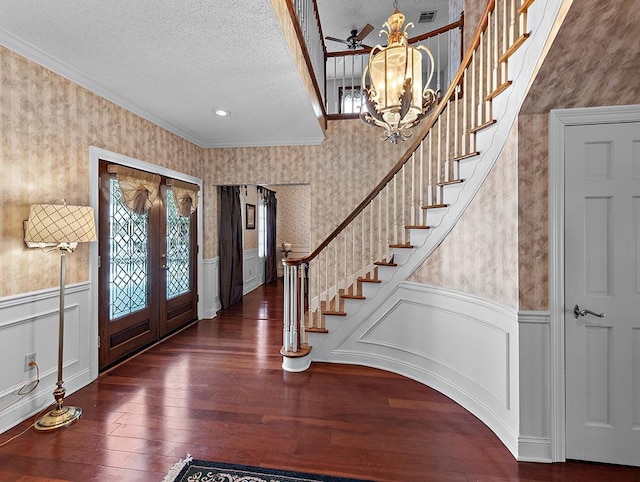 foyer entrance with ornamental molding, dark hardwood / wood-style floors, a textured ceiling, and french doors