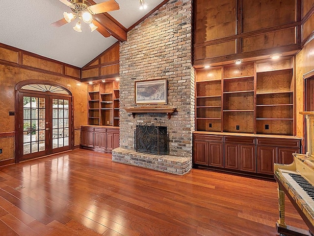 unfurnished living room featuring hardwood / wood-style flooring, a fireplace, a textured ceiling, french doors, and wood walls