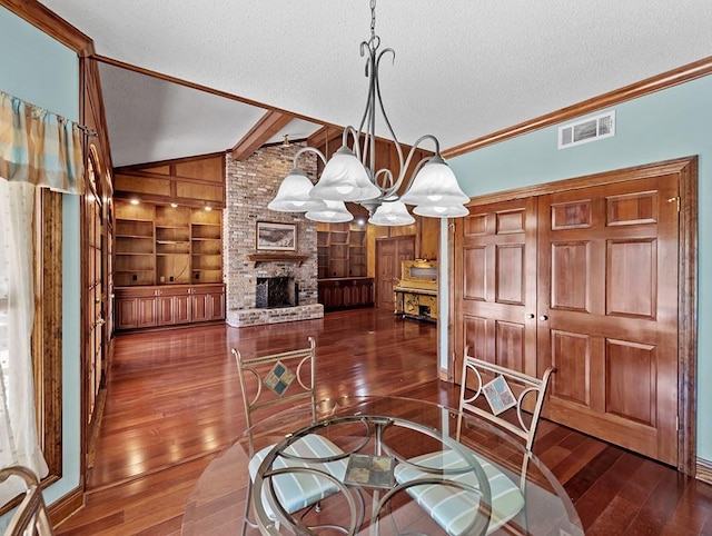 dining room featuring a fireplace, a textured ceiling, built in shelves, vaulted ceiling, and a chandelier