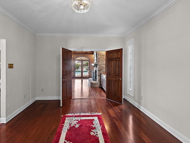 foyer entrance with crown molding, dark hardwood / wood-style flooring, and a textured ceiling