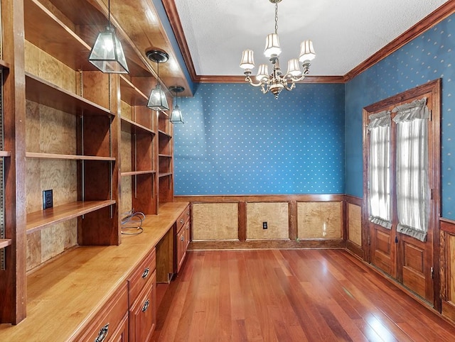 unfurnished dining area featuring an inviting chandelier, hardwood / wood-style floors, and crown molding