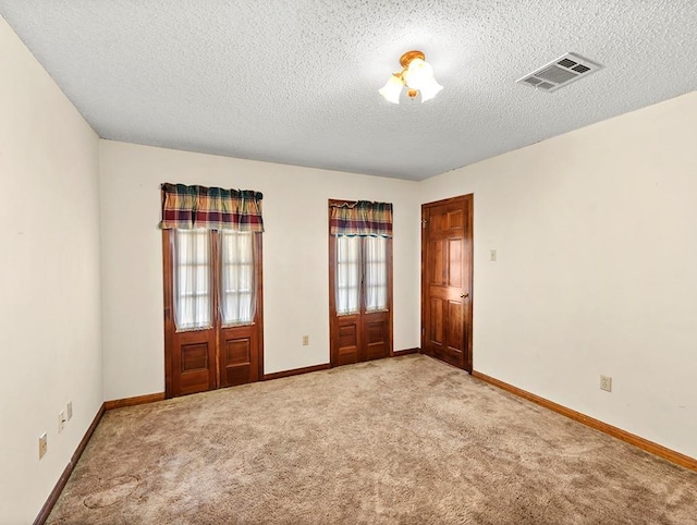 empty room with light colored carpet and a textured ceiling