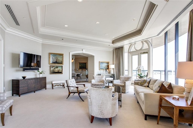 carpeted living room with ornamental molding and a tray ceiling