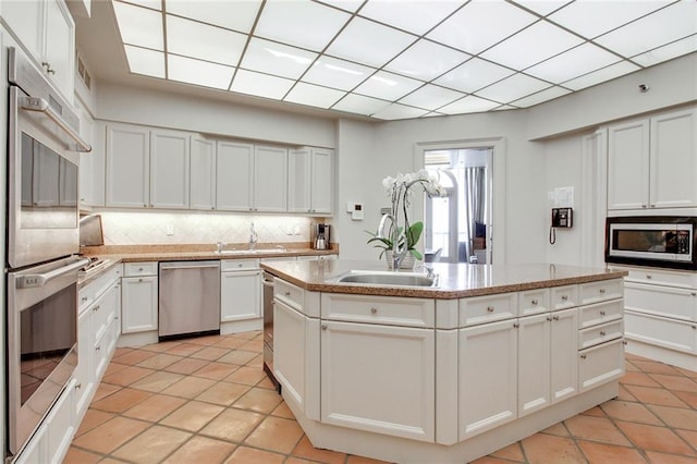 kitchen featuring sink, tasteful backsplash, an island with sink, stainless steel appliances, and white cabinets