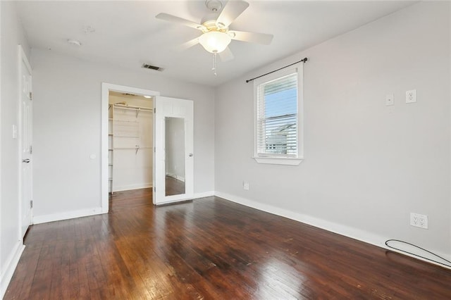 unfurnished bedroom with a walk in closet, dark hardwood / wood-style floors, ceiling fan, and a closet