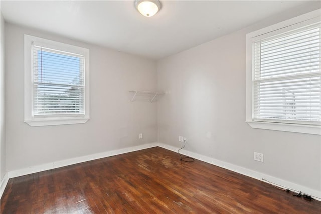 empty room featuring plenty of natural light and dark hardwood / wood-style flooring