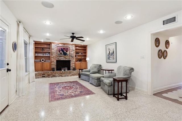 living room featuring built in shelves, a fireplace, and ceiling fan