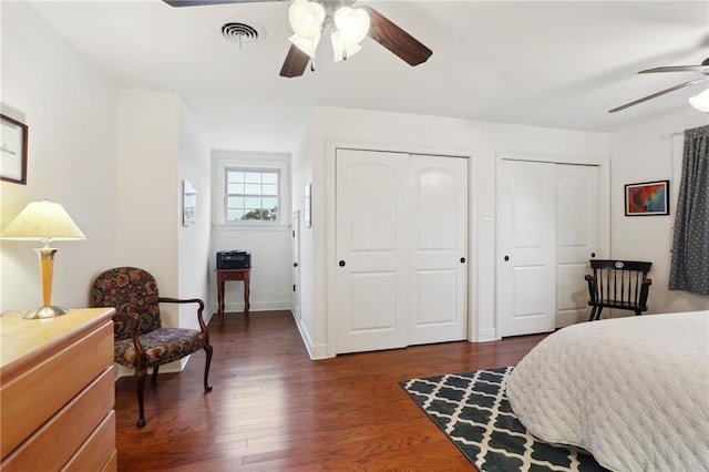 bedroom with multiple closets, ceiling fan, and dark wood-type flooring