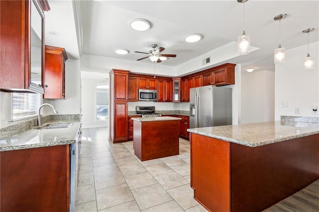 kitchen with sink, stainless steel appliances, a kitchen island, decorative light fixtures, and kitchen peninsula