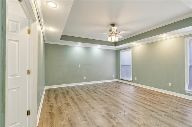 spare room with ceiling fan, ornamental molding, a tray ceiling, and light wood-type flooring