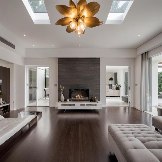 living room featuring wood-type flooring, a large fireplace, and a skylight