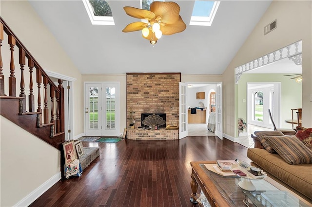 living room with hardwood / wood-style floors, high vaulted ceiling, a skylight, and a fireplace