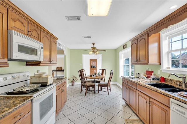 kitchen featuring white appliances, a wealth of natural light, sink, and dark stone counters