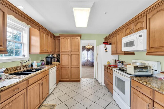 kitchen with sink, white appliances, light tile patterned floors, ceiling fan, and dark stone countertops