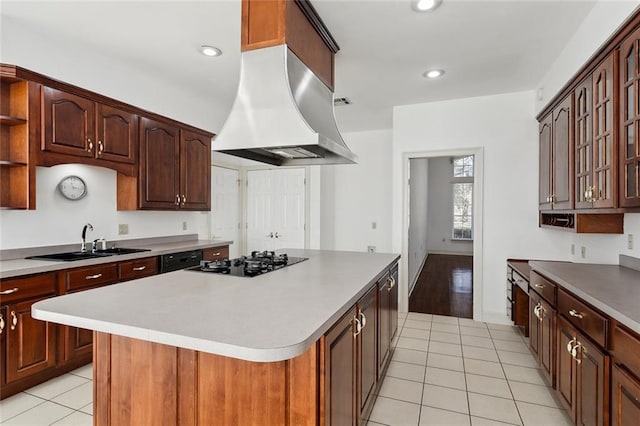 kitchen featuring a kitchen island, island range hood, sink, light tile patterned floors, and black appliances