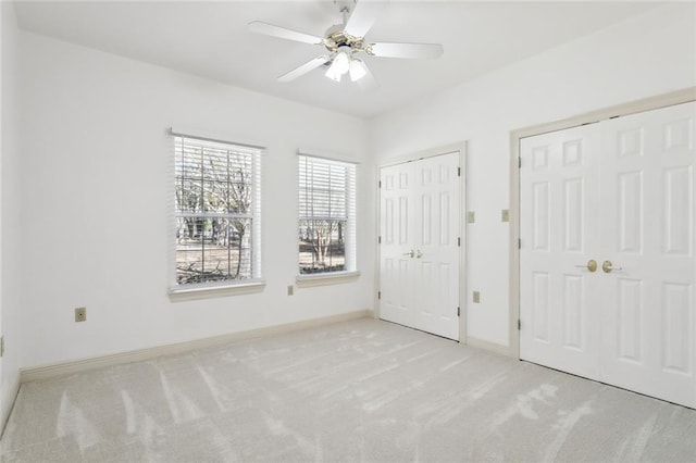 unfurnished bedroom with two closets, light colored carpet, and ceiling fan