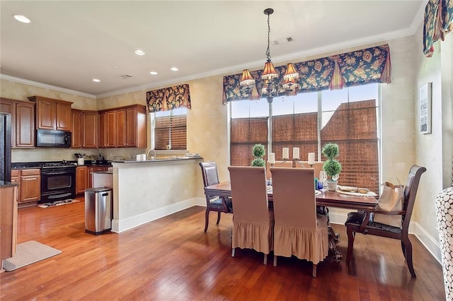 dining room featuring sink, hardwood / wood-style flooring, ornamental molding, and a chandelier